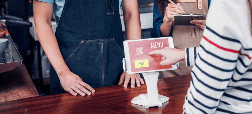 Person ordering a coffee through a self-serve kiosk. 