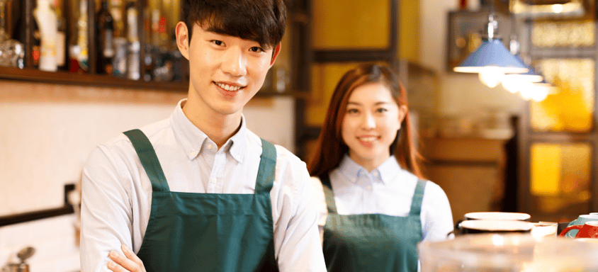 Two baristas standing in a coffee shop.