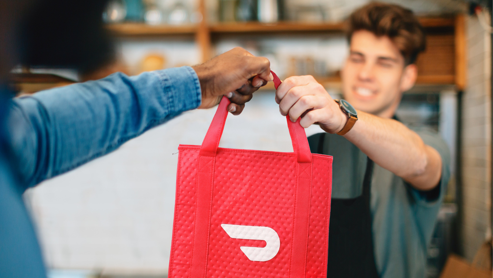 Server handing DoorDash order to delivery driver.