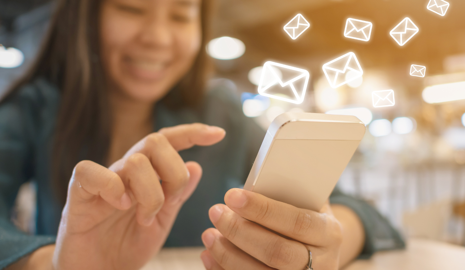 Woman using her hand to send message on mobile phone with email icons. 