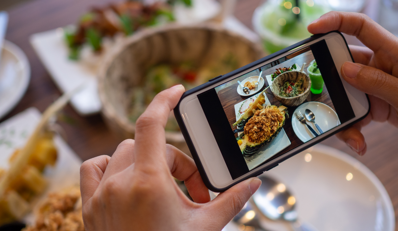 Person's hand taking a photo of their meal. 