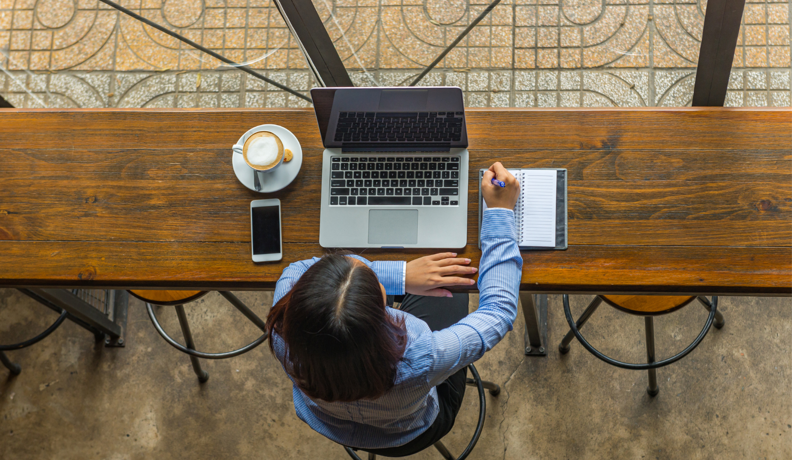 Top view of woman working on her laptop at a coffee shop. 