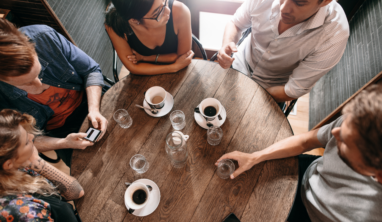 Group of coffee shop workers sitting around a table. 