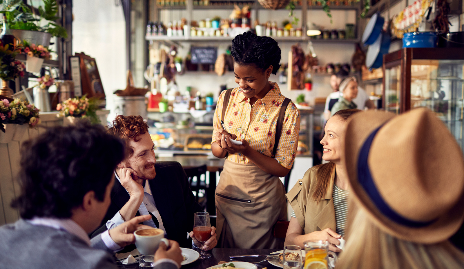A group of friends ordering food at their table in a cafe. 