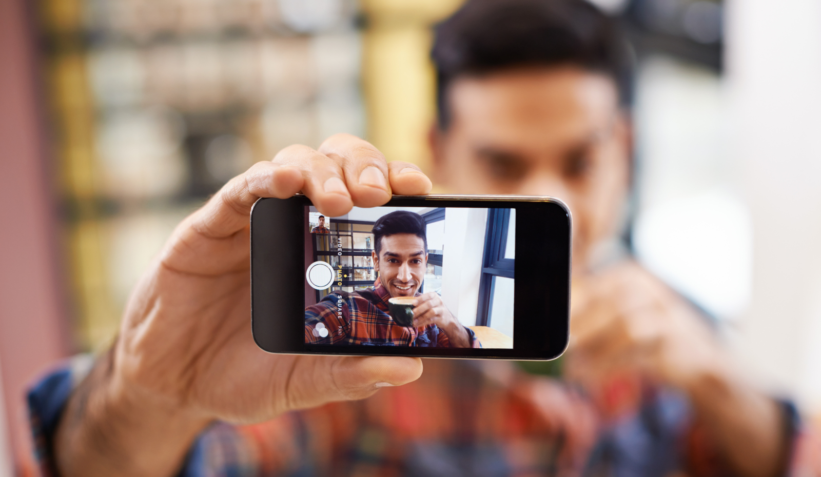 Man taking selfie in coffee shop. 